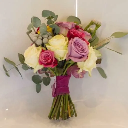 A bouquet of roses and greenery on a table.
